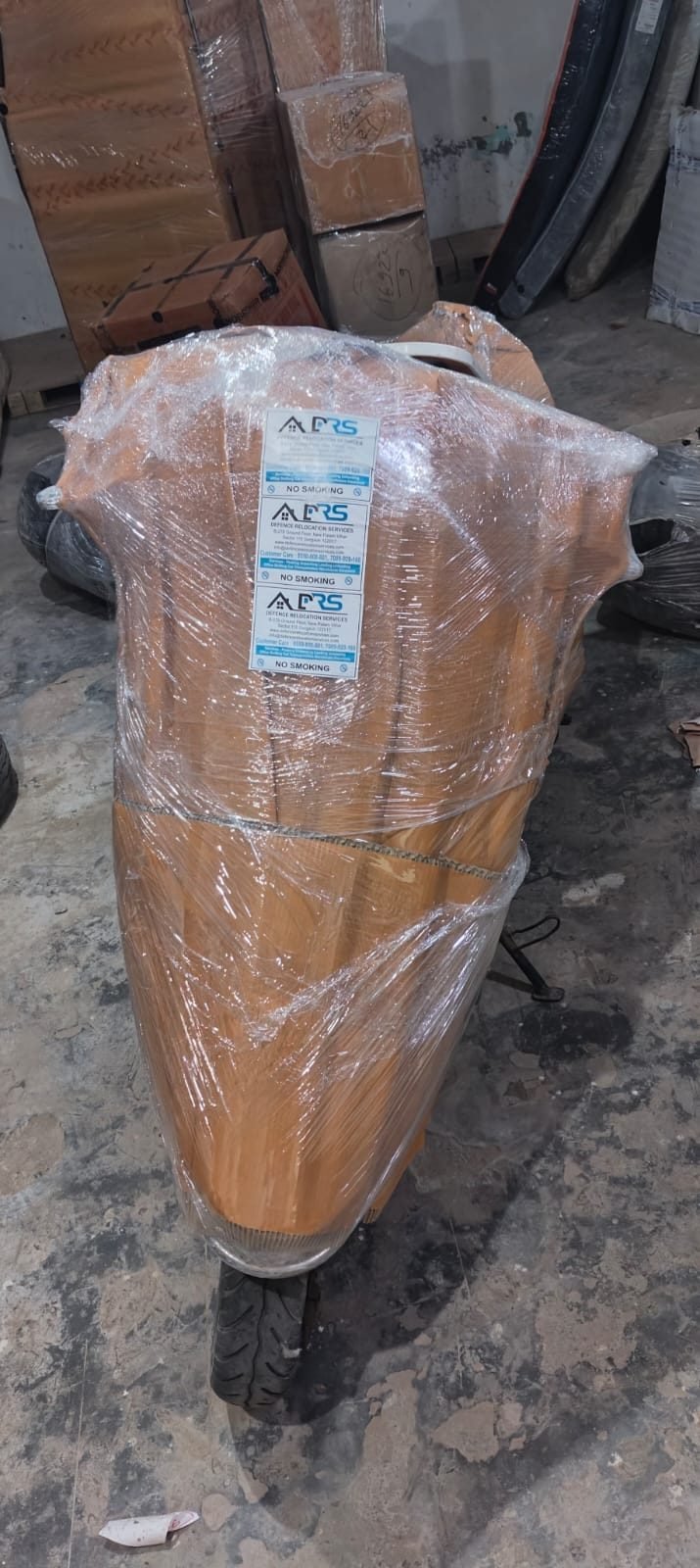 Two-wheeler wrapped and tagged with Defence Relocation Services labels for transport